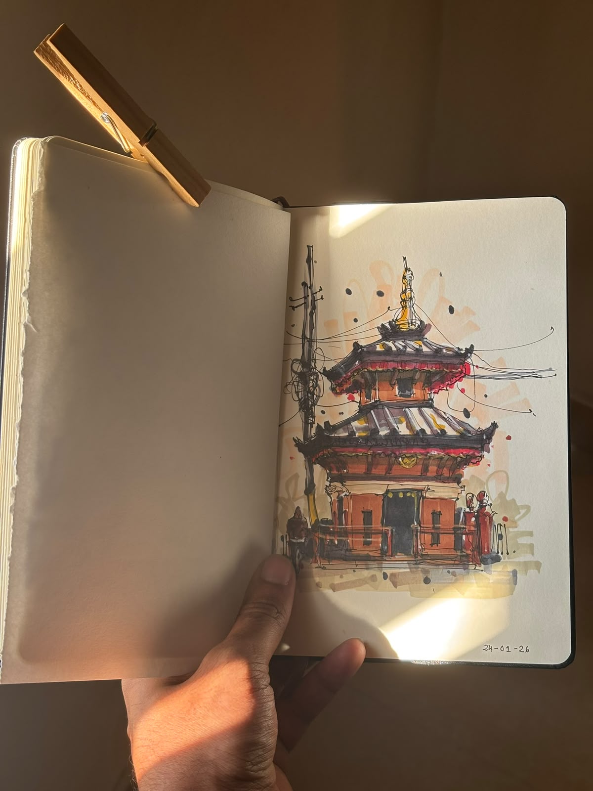 A hand holding an open architectural sketchbook